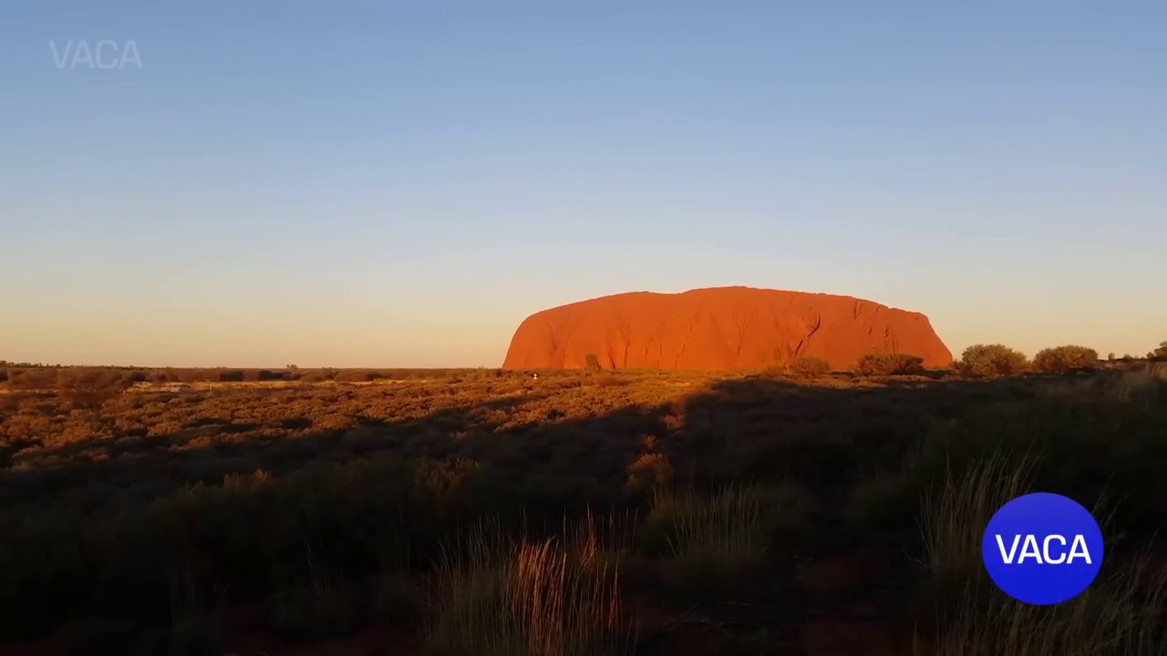 Núi đá Uluṟu hùng vĩ đổi màu dưới ánh hoàng hôn.