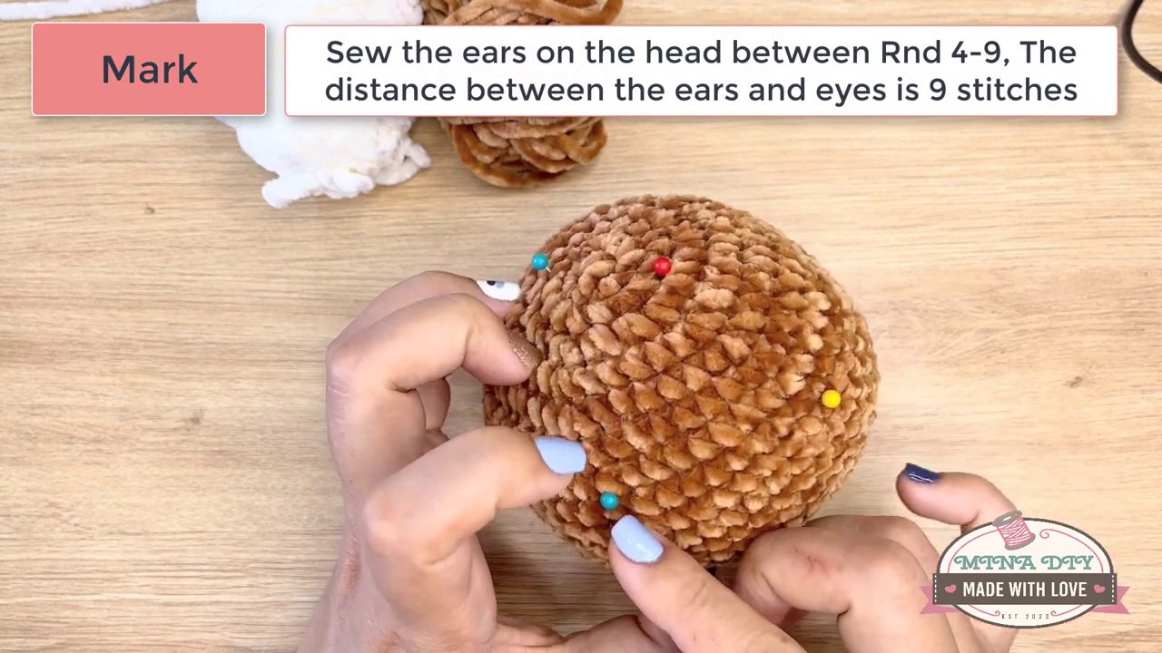 Bringing Your Amigurumi to Life: A Step-by-Step Guide to Embroidering Eyes and Noses 2 A close-up of the amigurumi's head being held steady, showcasing the two pre-placed black safety eyes with their washers secured inside.