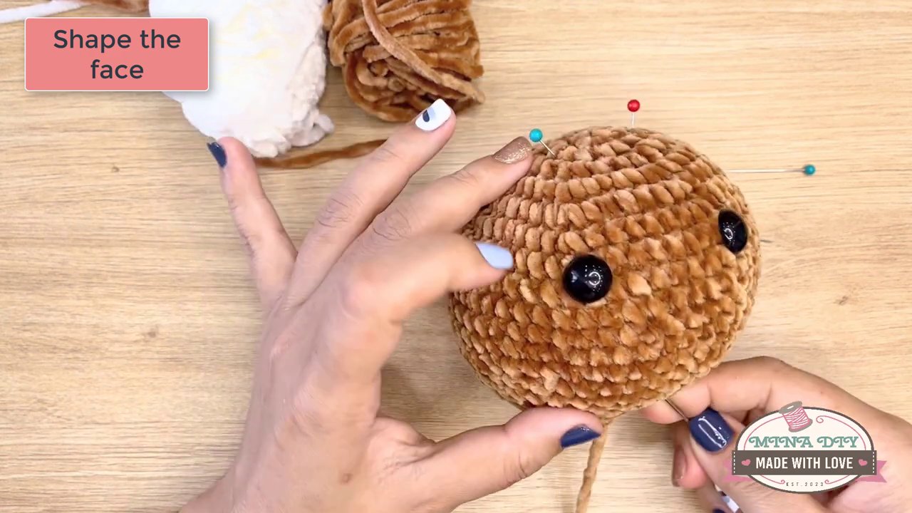 Bringing Your Amigurumi to Life: A Step-by-Step Guide to Embroidering Eyes and Noses 5 A close-up of a hand using black yarn to stitch a small, triangular nose directly onto the amigurumi's snout.