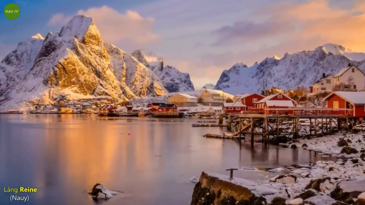 Cảnh quan ngoạn mục của Reine với những ngọn núi hùng vĩ bao quanh những ngôi nhà gỗ màu đỏ bên vịnh biển.